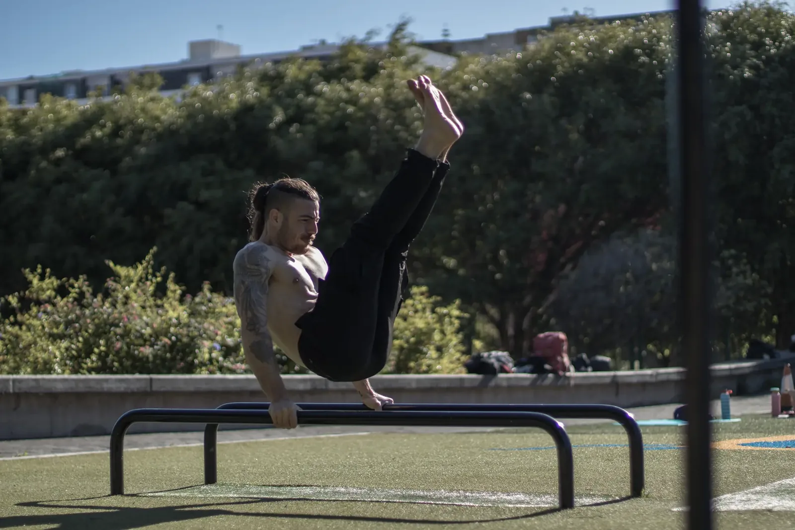 Atleta realizando un straddle press en paralelas durante un entrenamiento de calistenia al aire libre en Gran Canaria