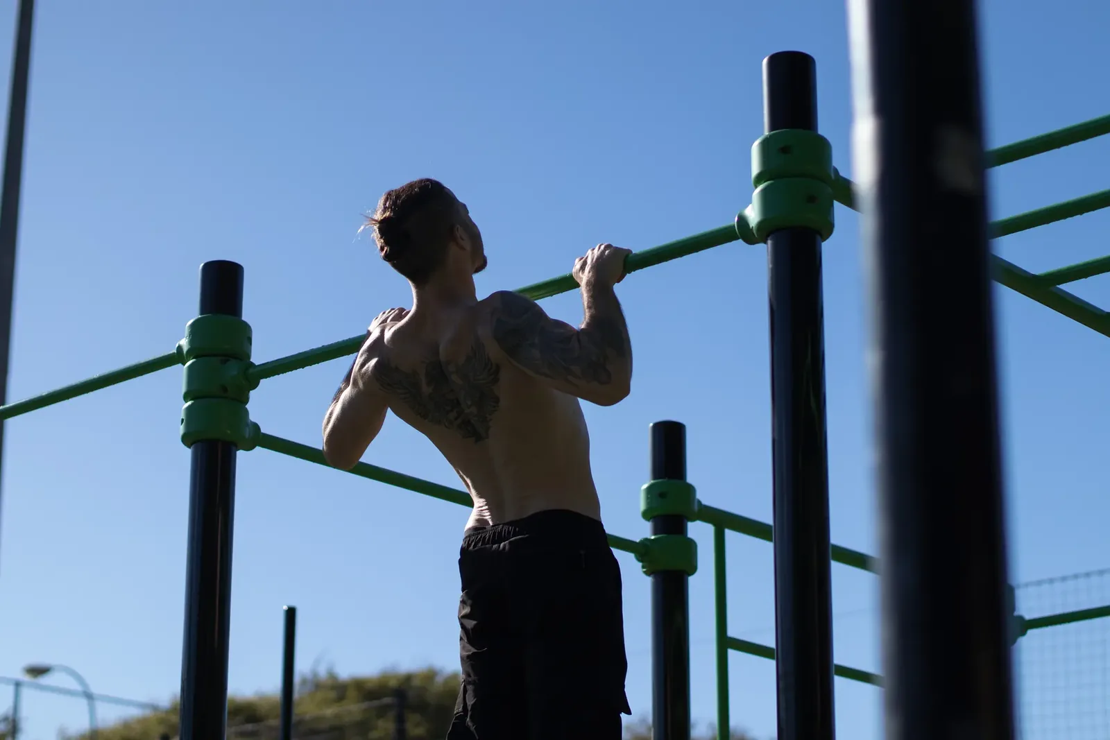 Atleta haciendo dominadas en barras de calistenia contra un cielo despejado en Gran Canaria